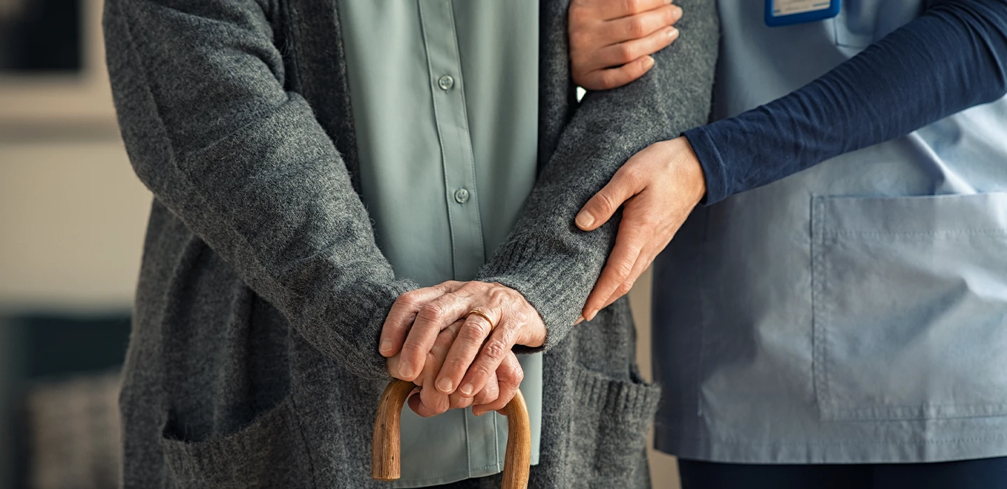 Caregiver from MeCare Staffing gently supporting a senior patient walking with a cane, symbolizing trust and attentive care.